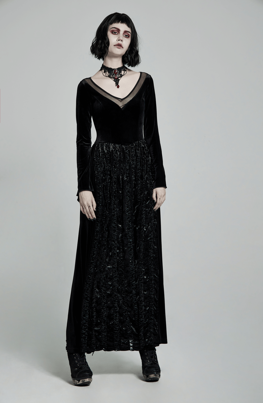 Gothic woman wearing an elegant black velvet dress with a lace necklace, showcasing a stylish gothic look.
