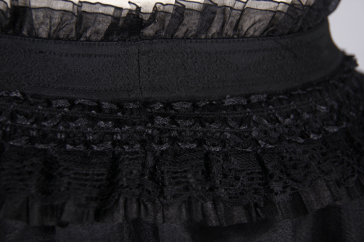 Close-up of the elastic waist of a gothic lace skirt, showcasing intricate ruffles and a punk-inspired design.