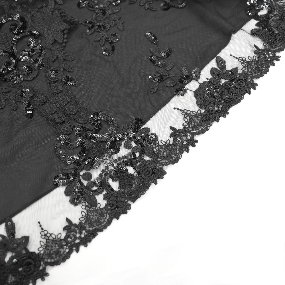 Close-up of gothic lace trim with intricate floral patterns and sequins on black fabric, enhancing a stylish maxi dress.