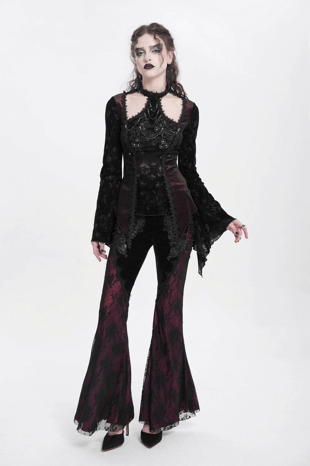 Gothic lace bell sleeved top with rose embellishments, paired with flared black and burgundy pants for a dark romantic look.