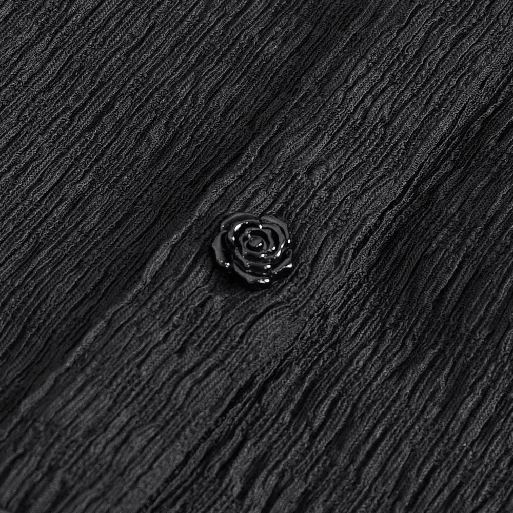 Close-up of a delicate black lace fabric with a glossy rose-shaped button, perfect for gothic fashion.