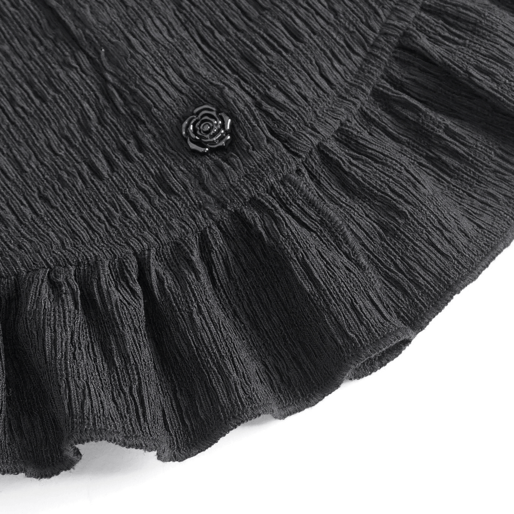Close-up of a black lace blouse ruffle hem with a decorative rose button detail, showcasing gothic elegance.