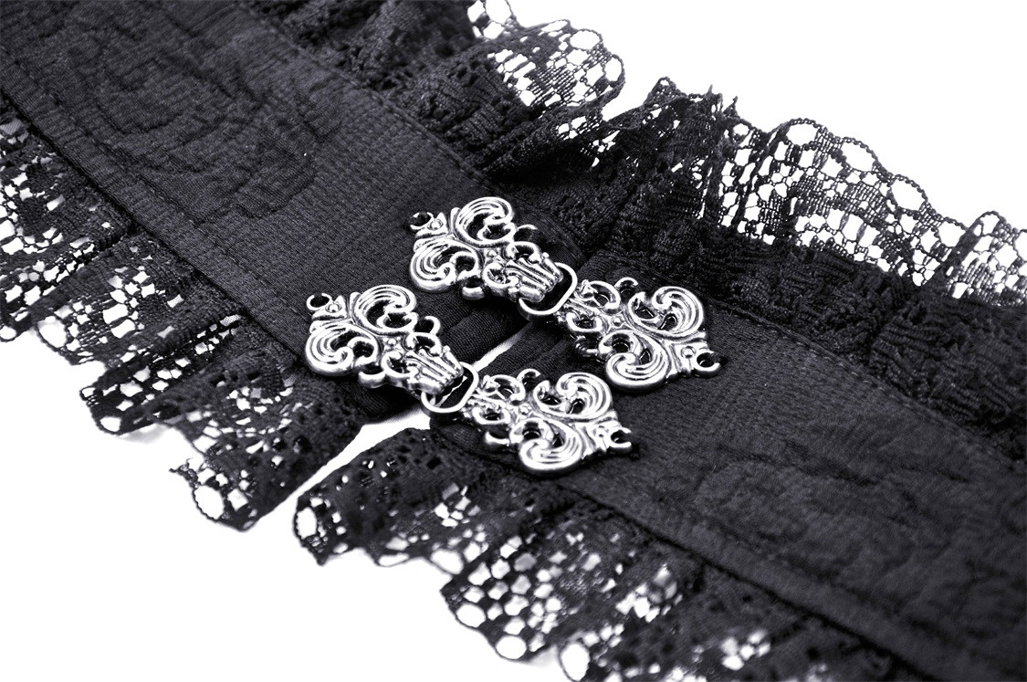 Close-up of intricate black lace with decorative silver clasp, perfect for gothic-inspired fashion details.