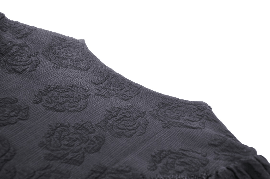 Close-up of intricate black jacquard fabric with rose patterns on gothic lace bolero.