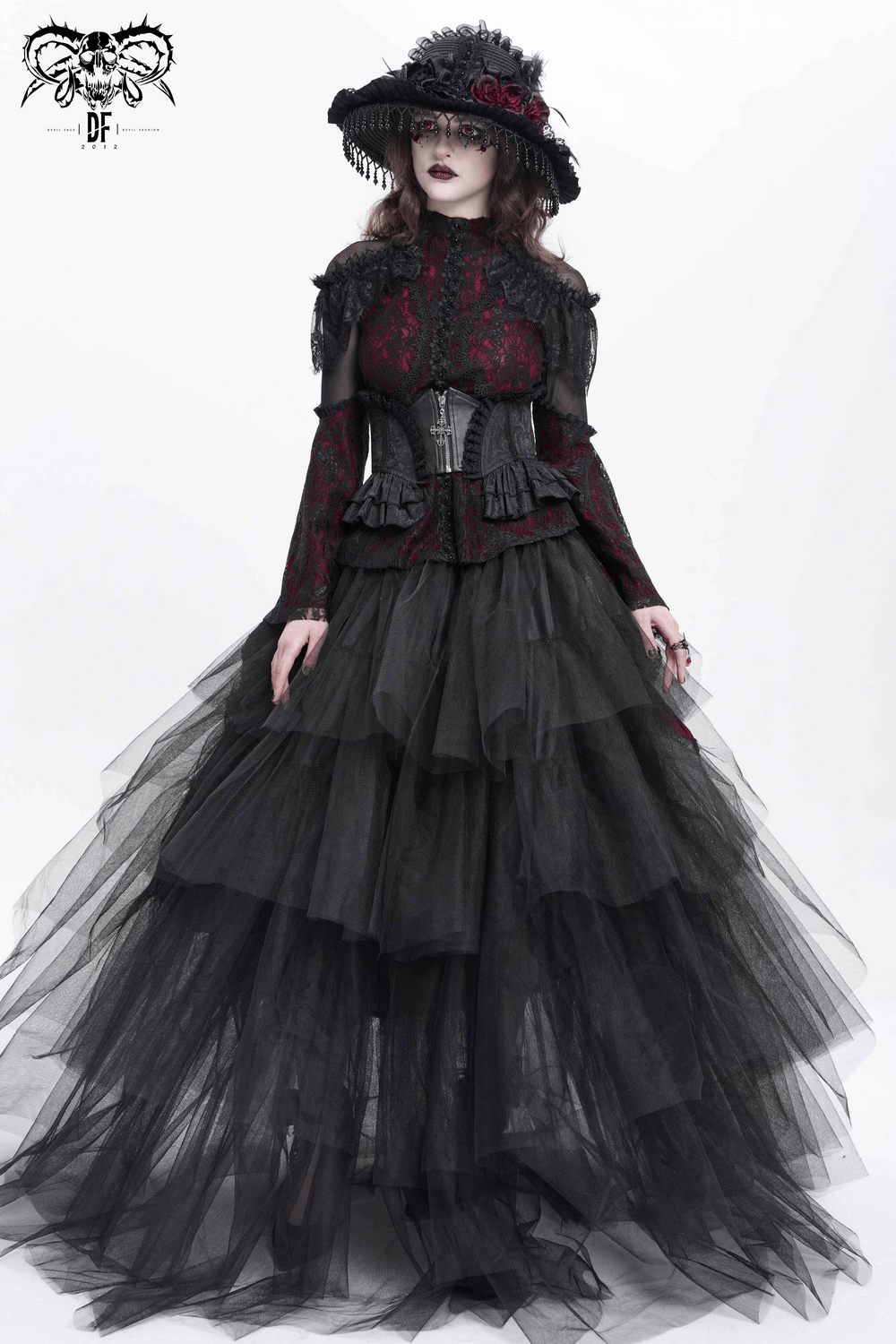 Model in a dramatic Gothic lace corset belt, black tiered tulle skirt, and ornate hat, showcasing dark Victorian aesthetics.