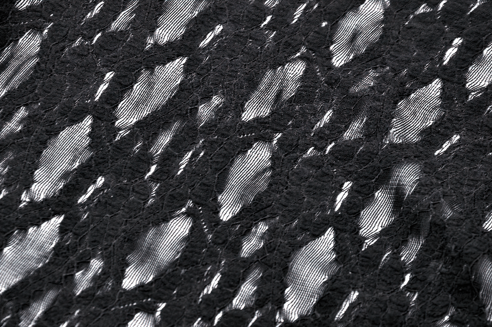 Close-up of intricate black lace fabric featuring a unique textured pattern, ideal for gothic fashion designs.