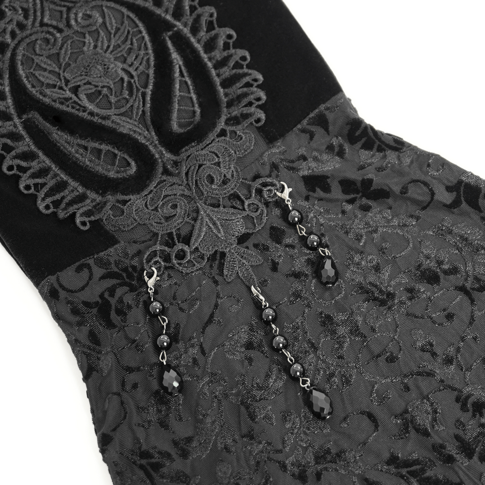 Close-up of gothic velvet pants with intricate lace embroidery and decorative bead accents for an edgy fashion statement.