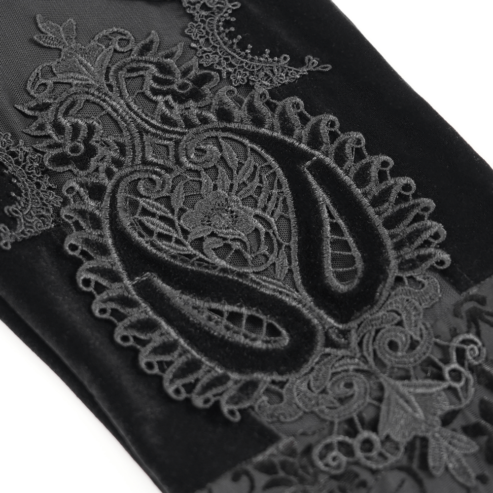 Close-up of intricate black embroidery and lace detailing on gothic velvet flare pants.