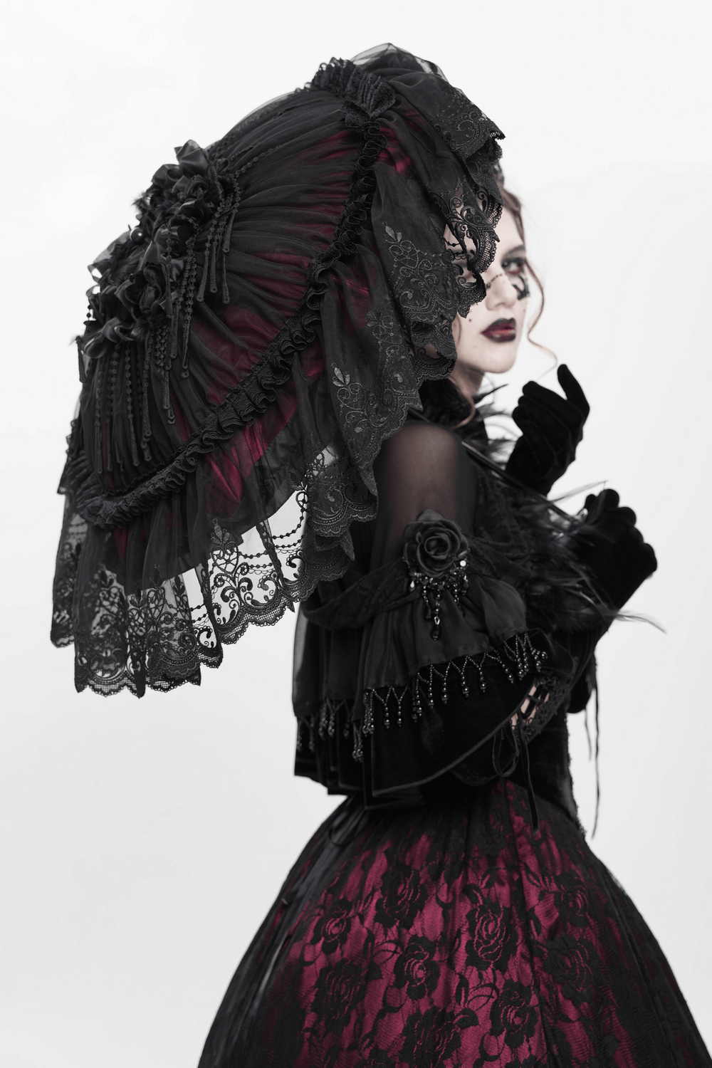 Gothic lace umbrella with roses, fringe, and satin detail, worn in a vintage-inspired look, exuding elegance.