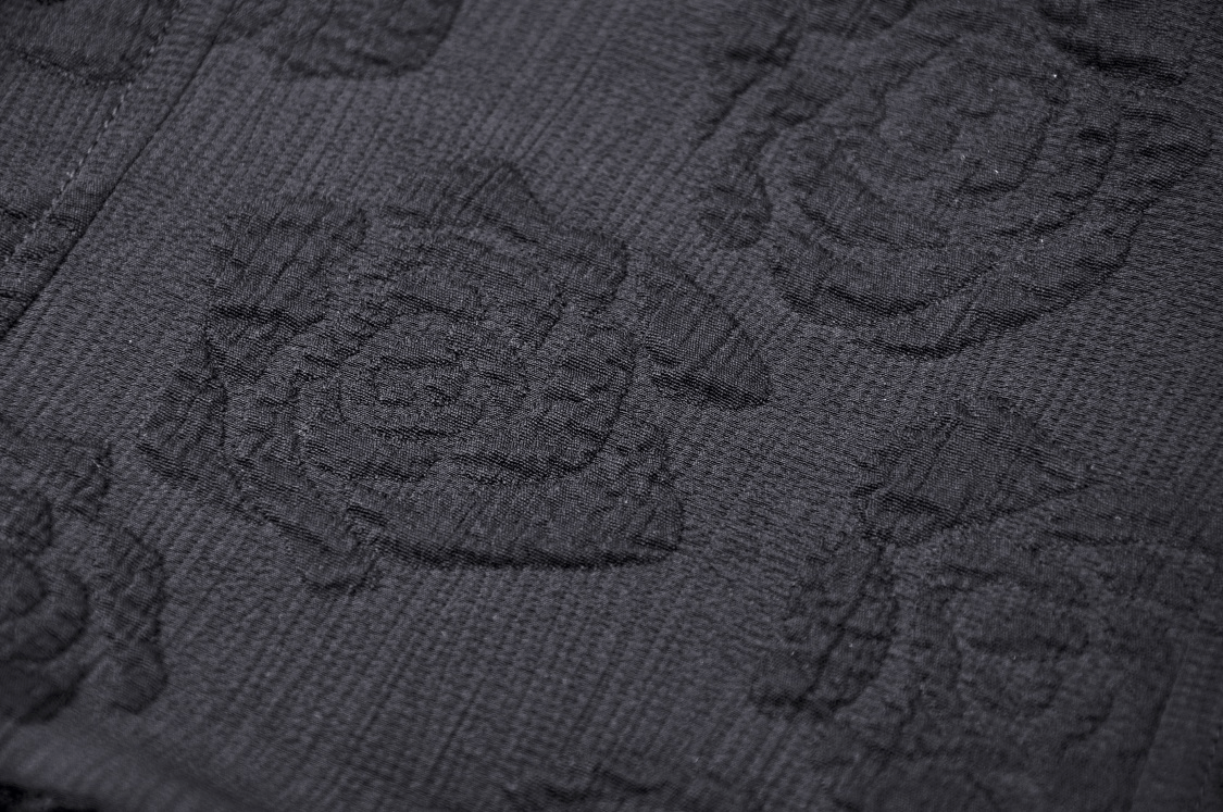 Textured black fabric featuring an intricate rose pattern, perfect for gothic-inspired fashion designs.