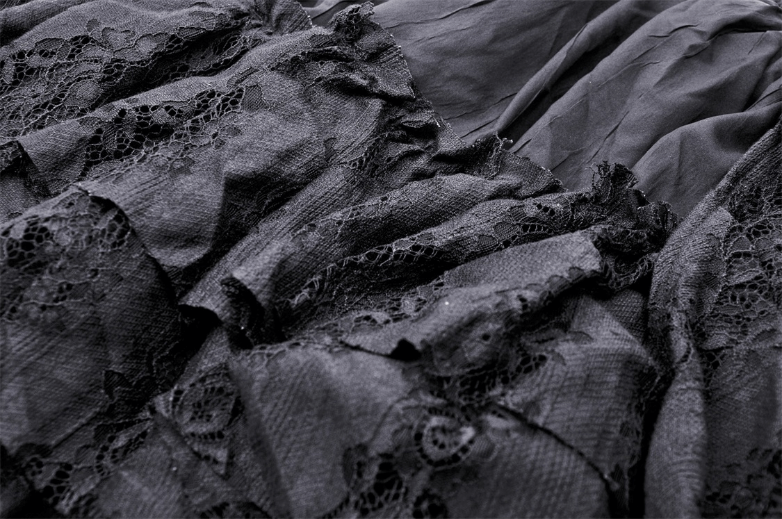 Close-up of elegant black lace with romantic ruffles, showcasing the intricate design of a gothic high-low skirt.