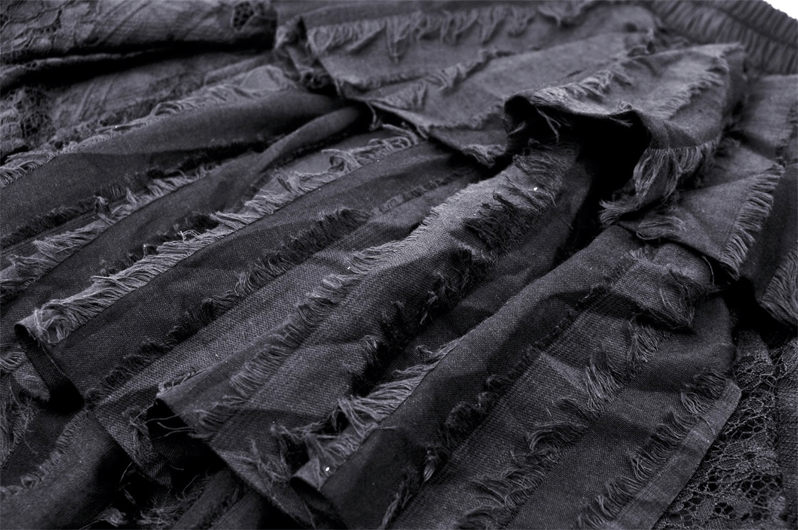 Close-up of black lace high-low skirt with romantic ruffles, showcasing textured fabric and asymmetrical design.