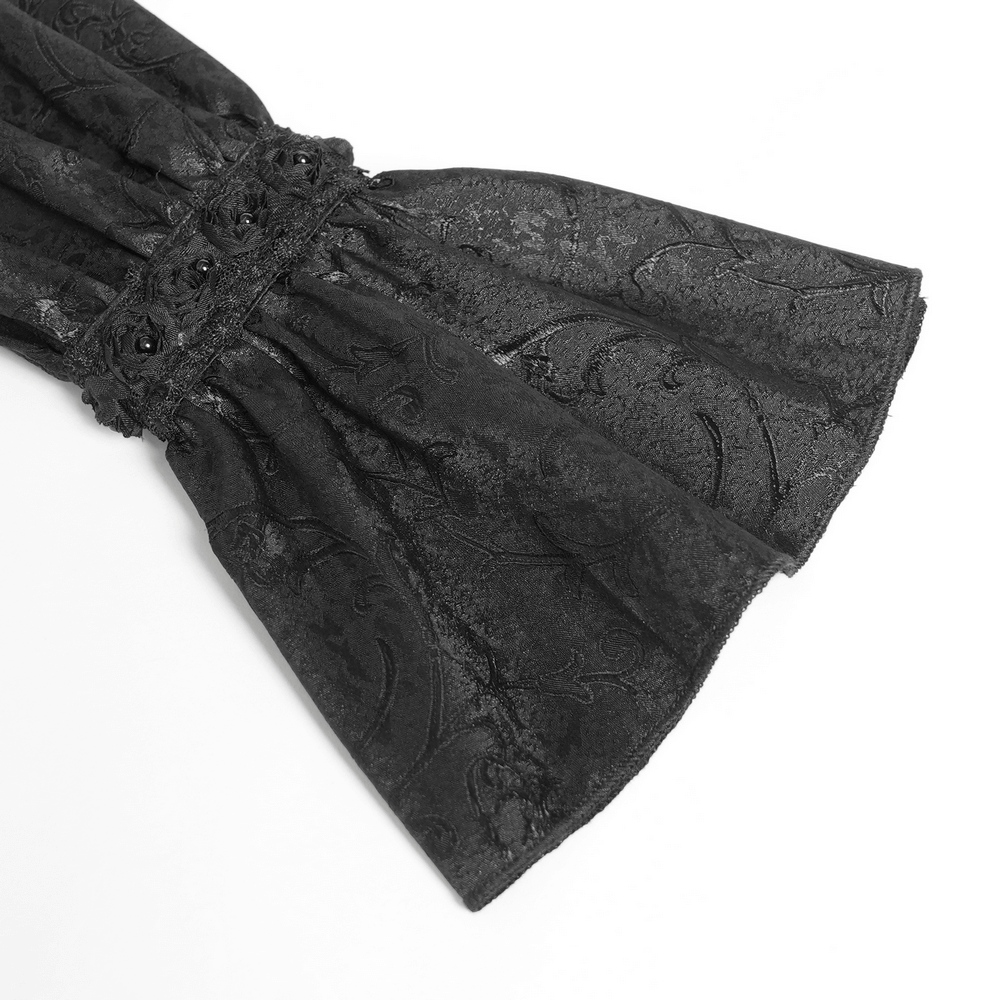 Close-up of black lace puff sleeve with elegant floral jacquard fabric and intricate button details.