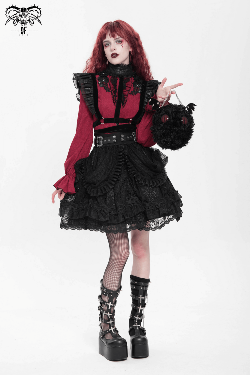 Gothic fashion model in layered black lace skirt with ruffles, red blouse, and steampunk accessories.