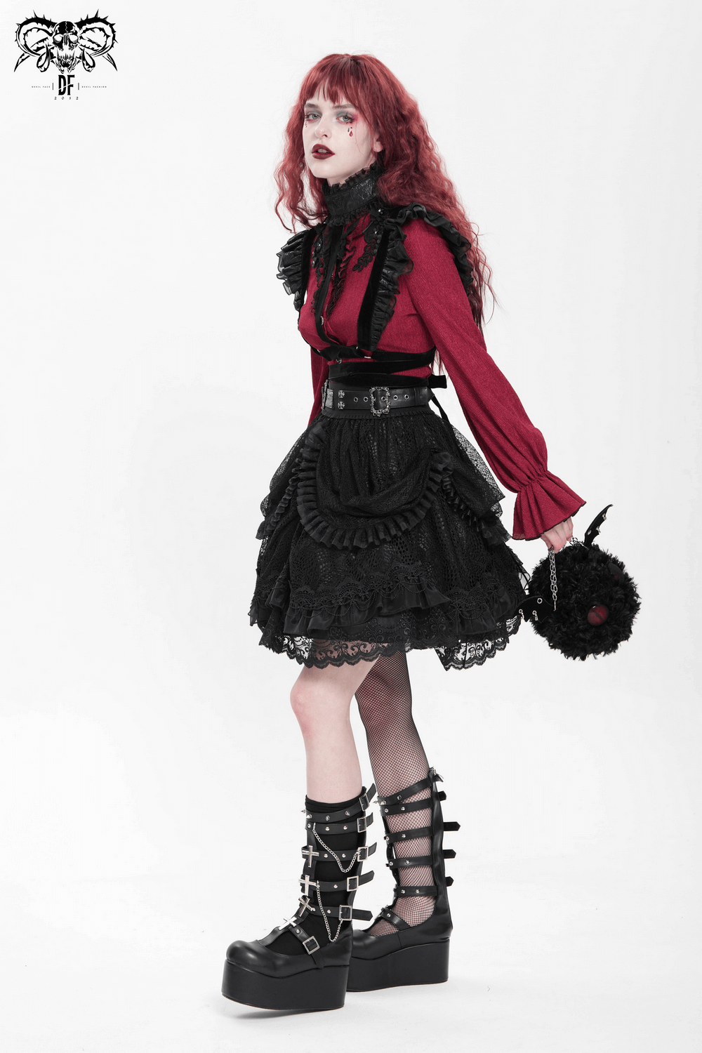 Model wearing a gothic lace layered skirt with belts and ruffled drapes, paired with a stylish red top and platform boots.