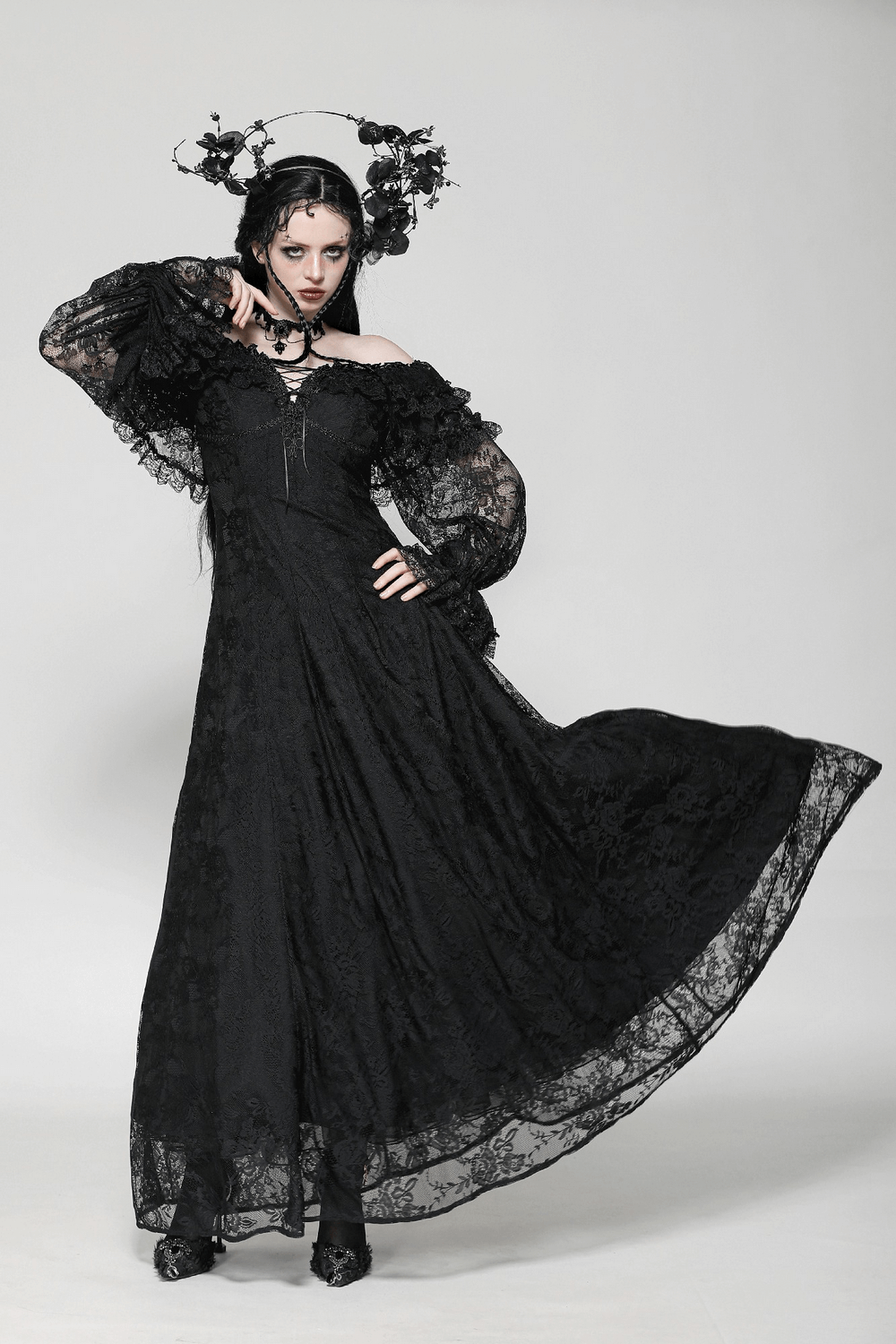 Gothic lace off-shoulder dress with corset back and ruffles, model posing dramatically in black fabric.