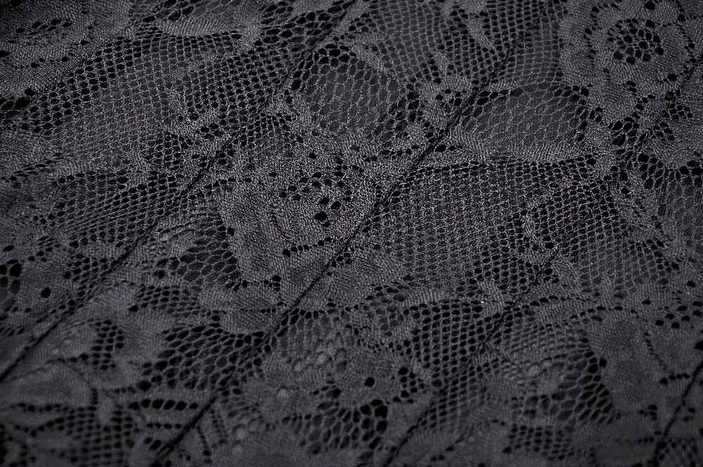 Close-up of intricate black lace fabric with floral patterns, perfect for a gothic off-shoulder dress.