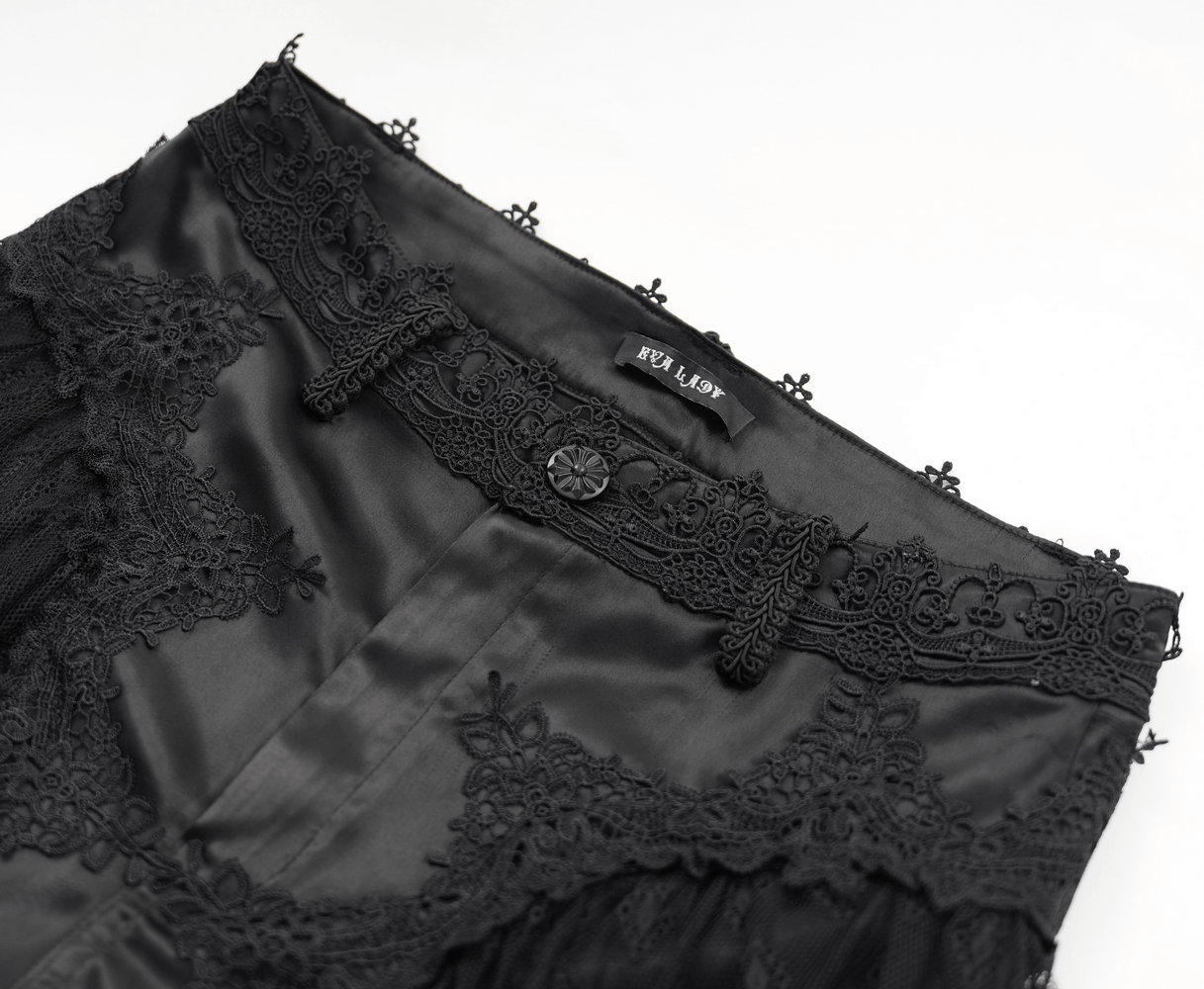 Close-up of intricate lace and satin detailing on Gothic lace overlay bell-bottom pants.