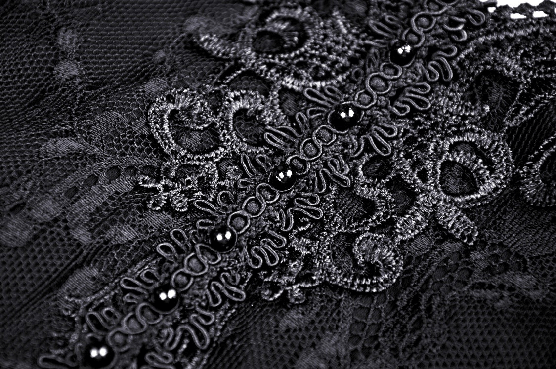Close-up of intricate black lace with floral patterns and beaded detailing, perfect for gothic fashion.