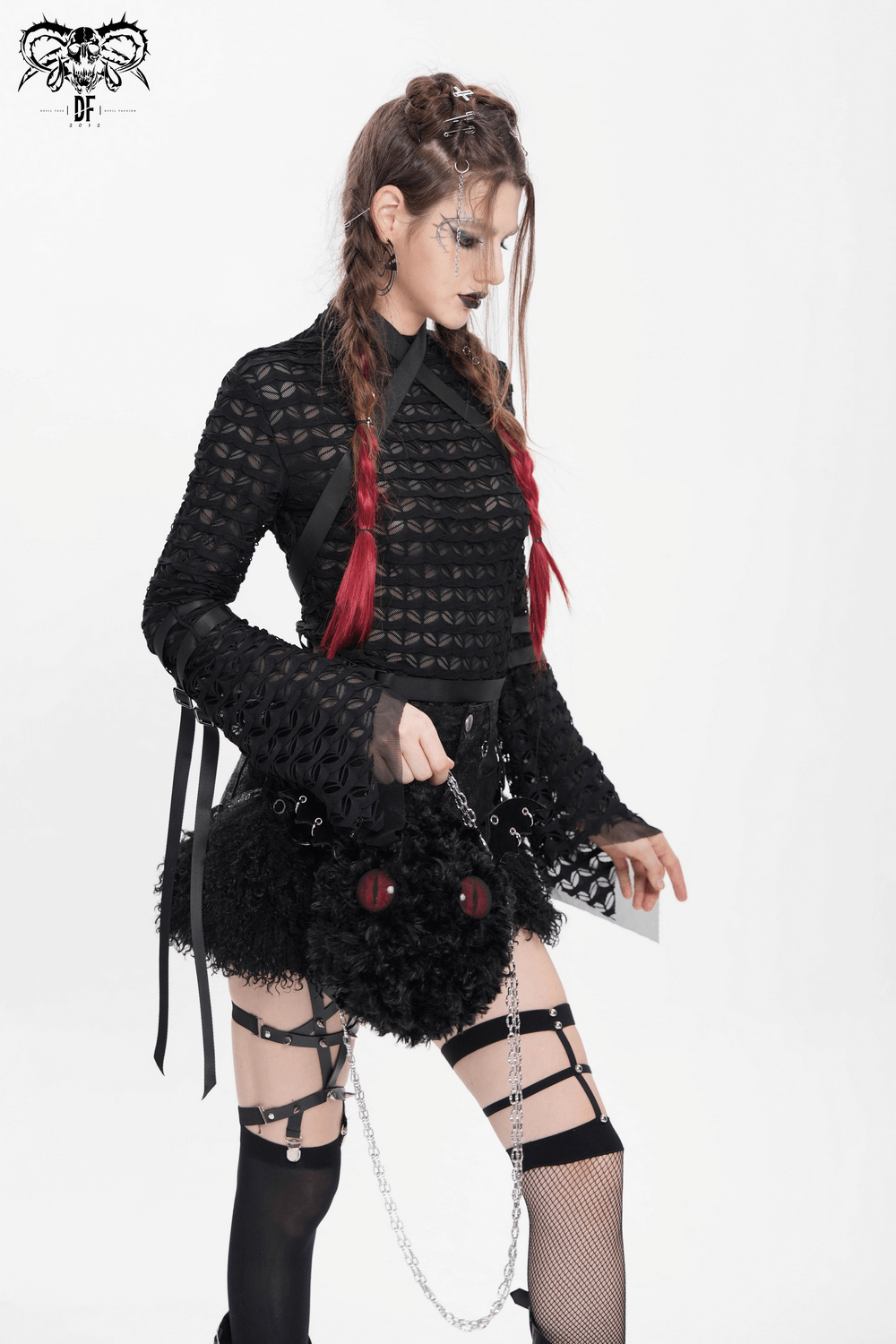 Alternative gothic fashion model in sheer lace top with red accents and edgy accessories, showcasing a punk-inspired look.