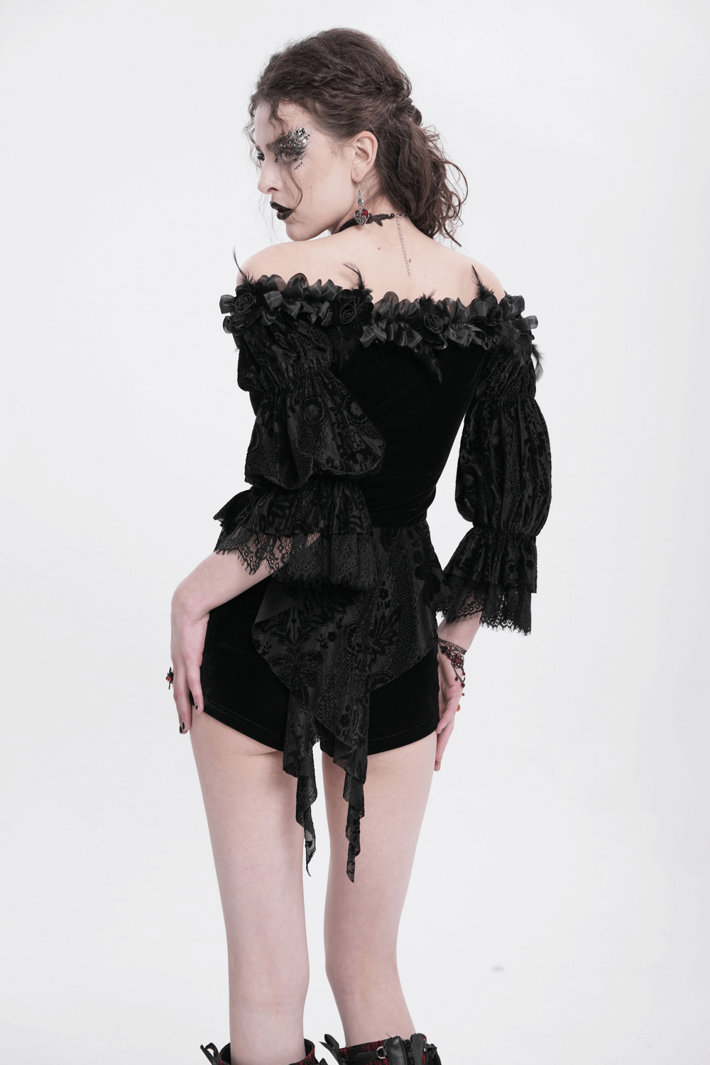 Back view of a gothic lace-trimmed off-shoulder velvet blouse with floral details and dramatic sleeves.