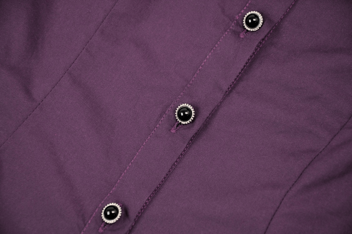 Close-up of dark purple blouse fabric with elegant black buttons for a vintage-inspired look.