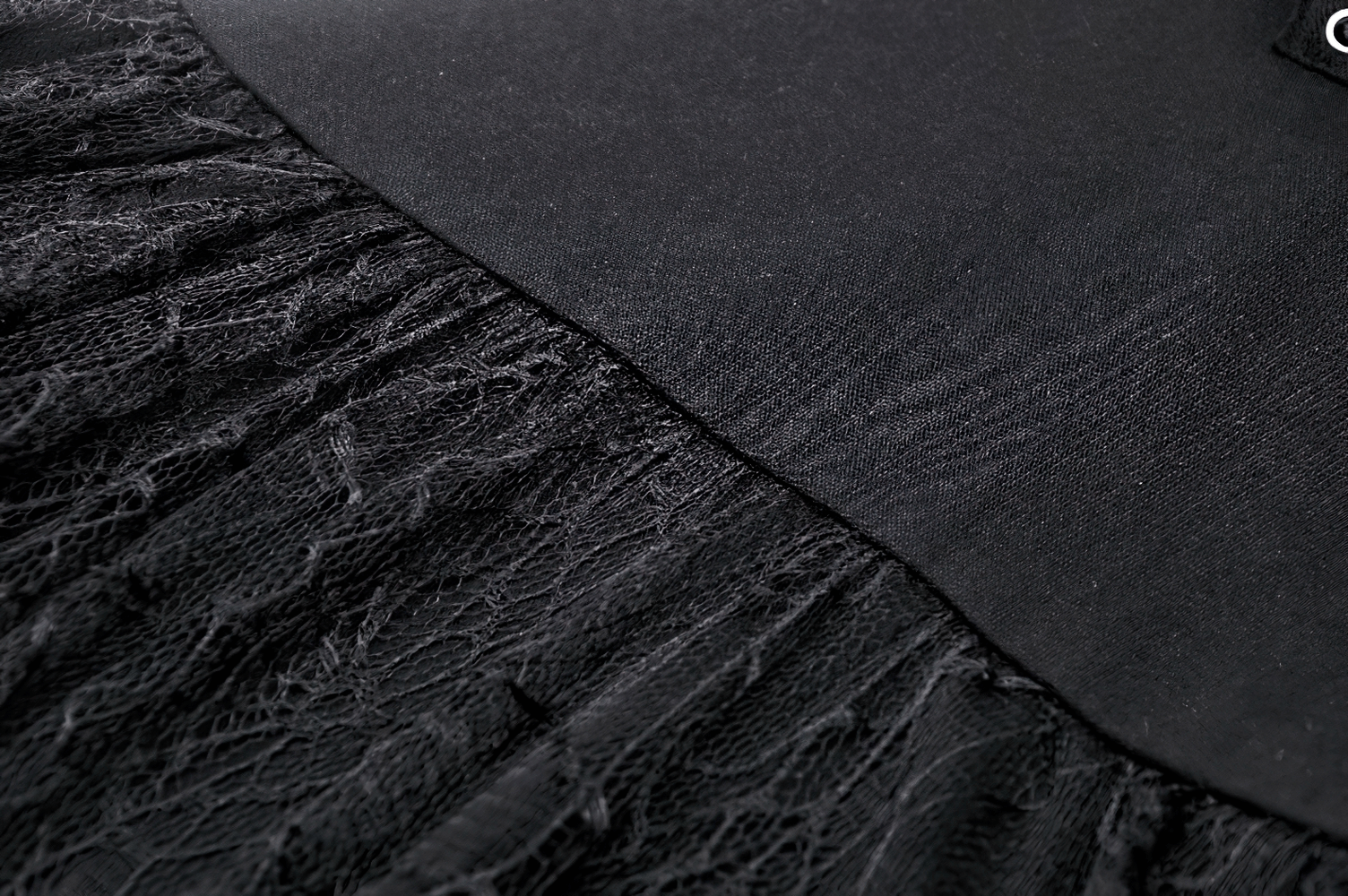 Close-up of black dress fabric featuring spider web lace and smooth satin for gothic elegance.