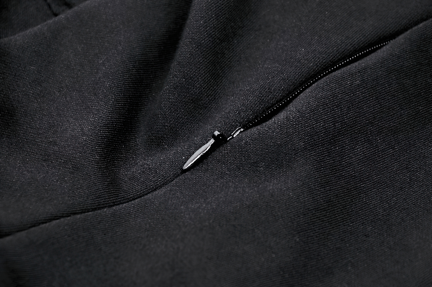 Close-up of black fabric featuring a zipper detail, perfect for gothic dress designs.
