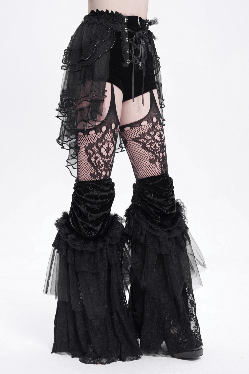 Gothic lace-up black ruffled shorts with tulle and tie detail, styled with fishnet leggings and dramatic layered ruffles.