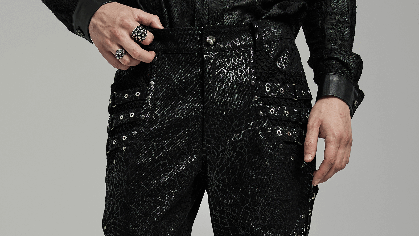 Close-up of men's gothic lace-up black twill flare pants featuring rivets and mesh side details.
