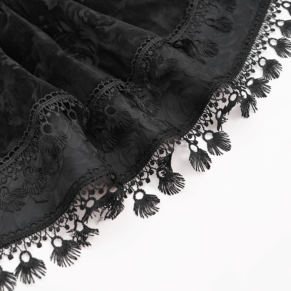 Close-up of black velvet skirt hem featuring intricate lace trim and tassels, embodying Victorian Gothic style.