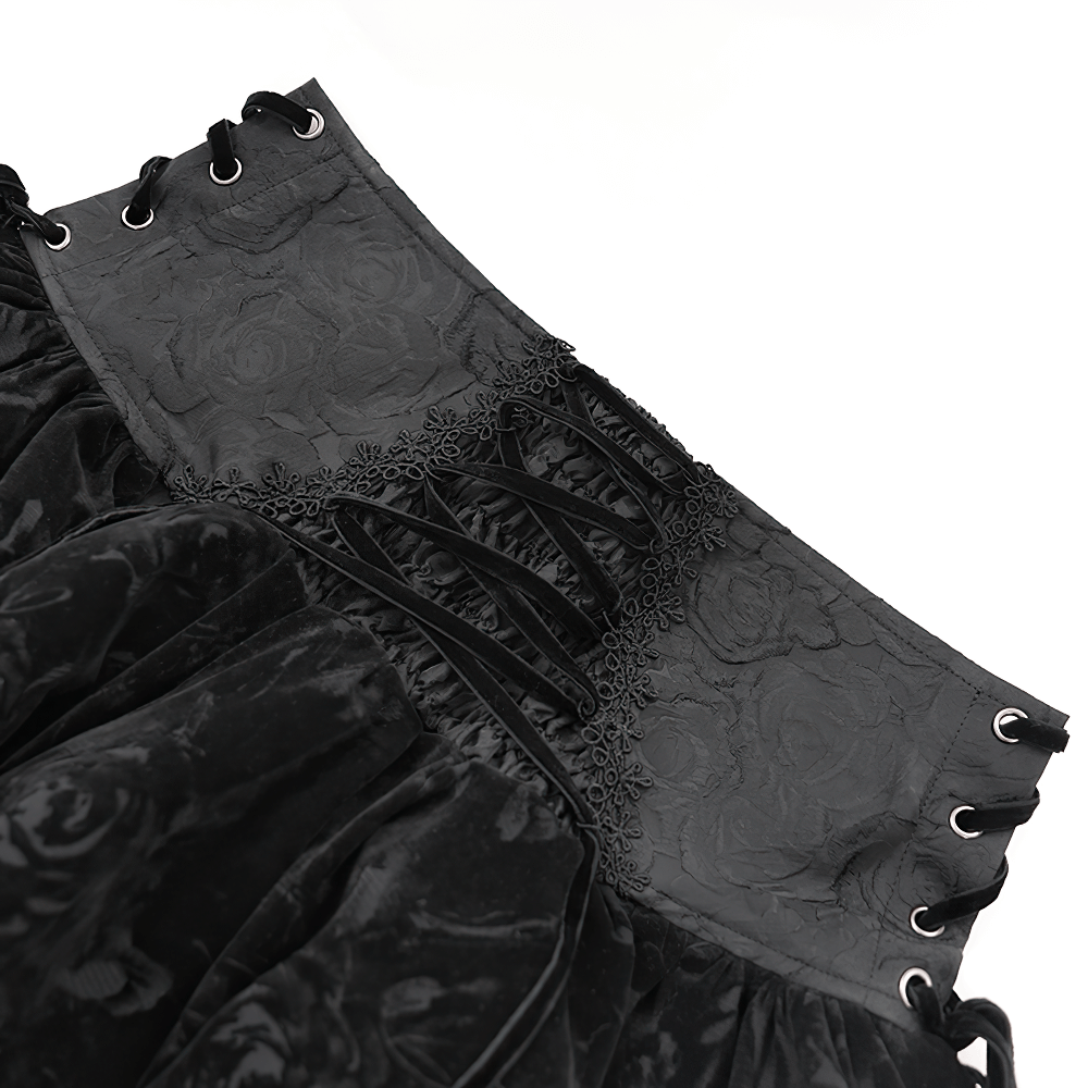 Close-up of gothic black velvet skirt's corset-style waistband with lace-up details and floral texture.