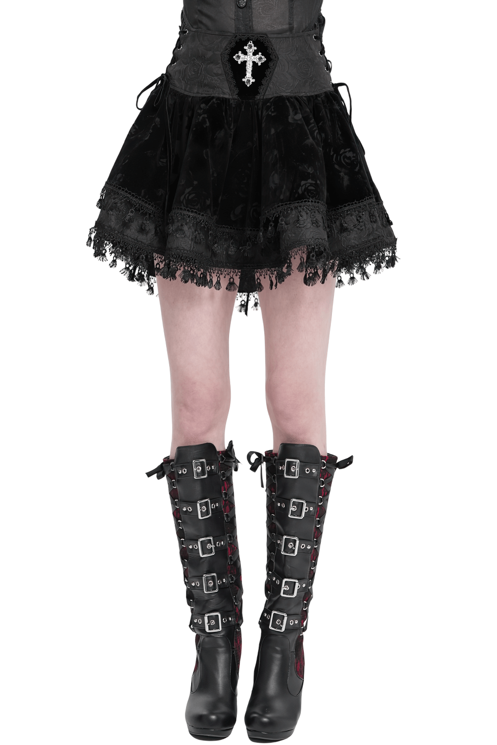 Gothic black velvet skirt with lace-up detail, embroidered cross, and tassel hem, paired with edgy knee-high boots.