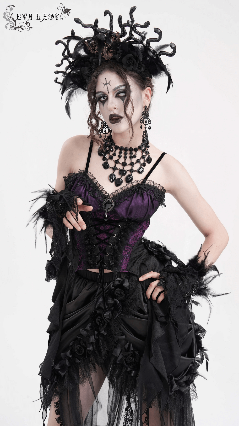 Model in a Gothic lace-up corset top with floral accents, featuring purple and black detailing and dramatic accessories.