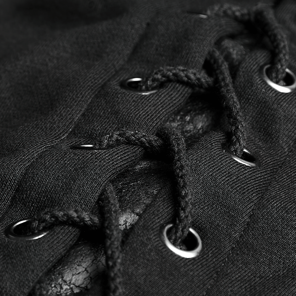 Close-up of gothic lace-up detailing with faux leather and silver grommets on a black coat.