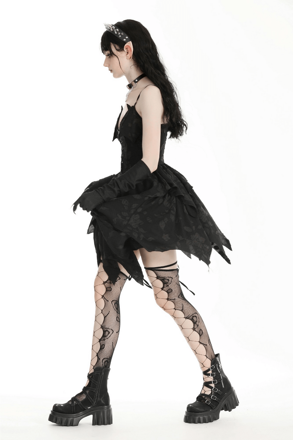 Gothic lace-up black dress with ruffled hem, paired with fishnet stockings and chunky boots for dark elegance.