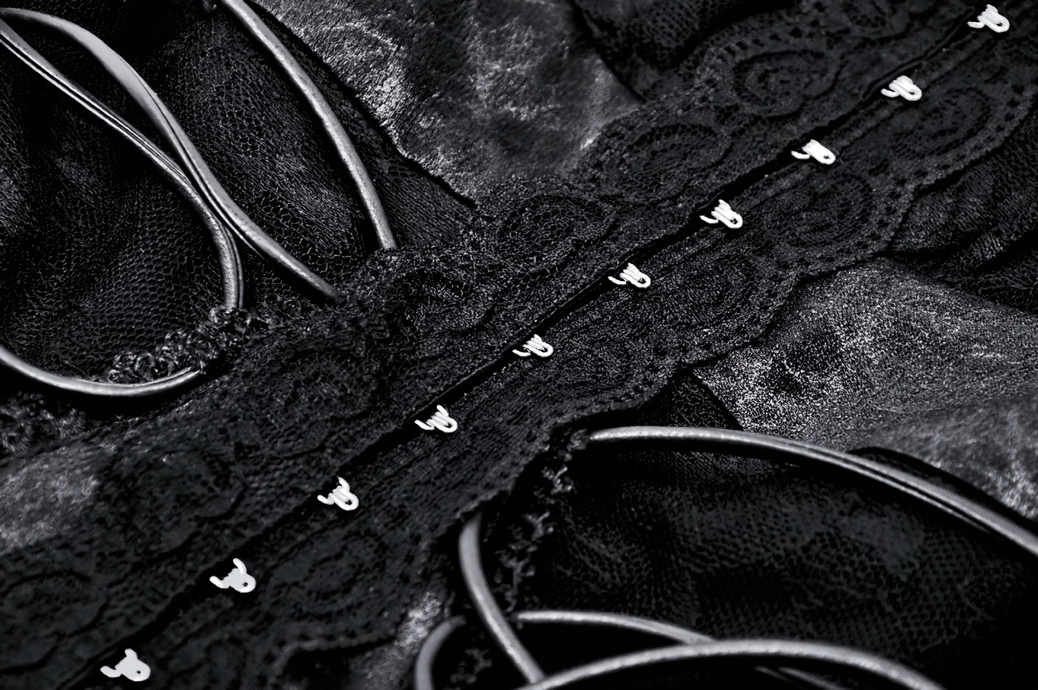 Close-up of intricate lace trim and lacing details on a Gothic-inspired black top textile.