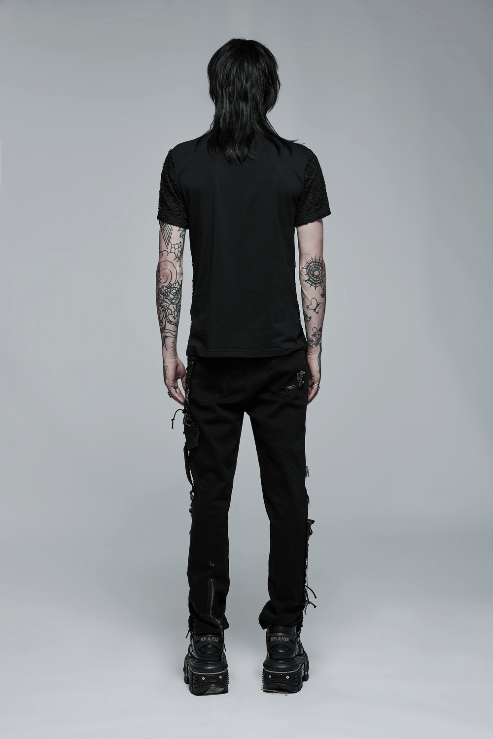 Back view of a model in a Gothic Lace-Up V-Neck Mesh Tee, showcasing an edgy style with tattoos and black pants.