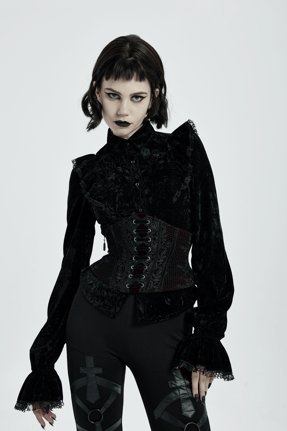 Gothic model in a black velvet corset with red lace accents, showcasing vintage style and intricate detailing.