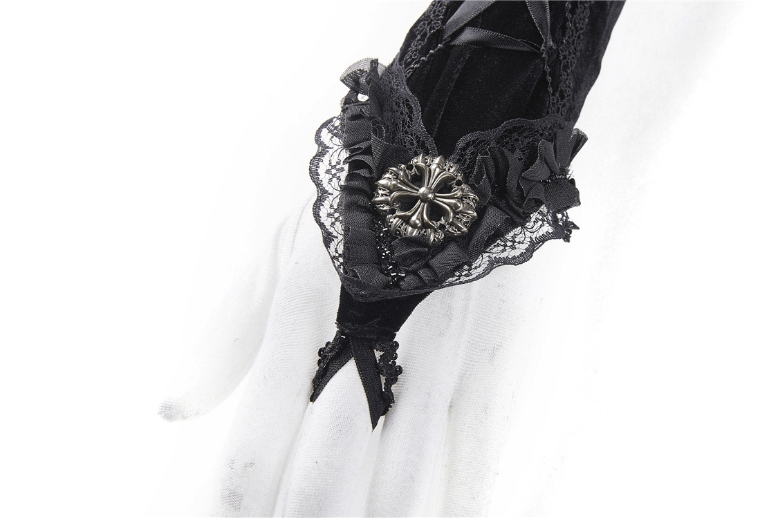 Close-up of black lace-up velvet fingerless gloves featuring intricate lace and a decorative brooch.