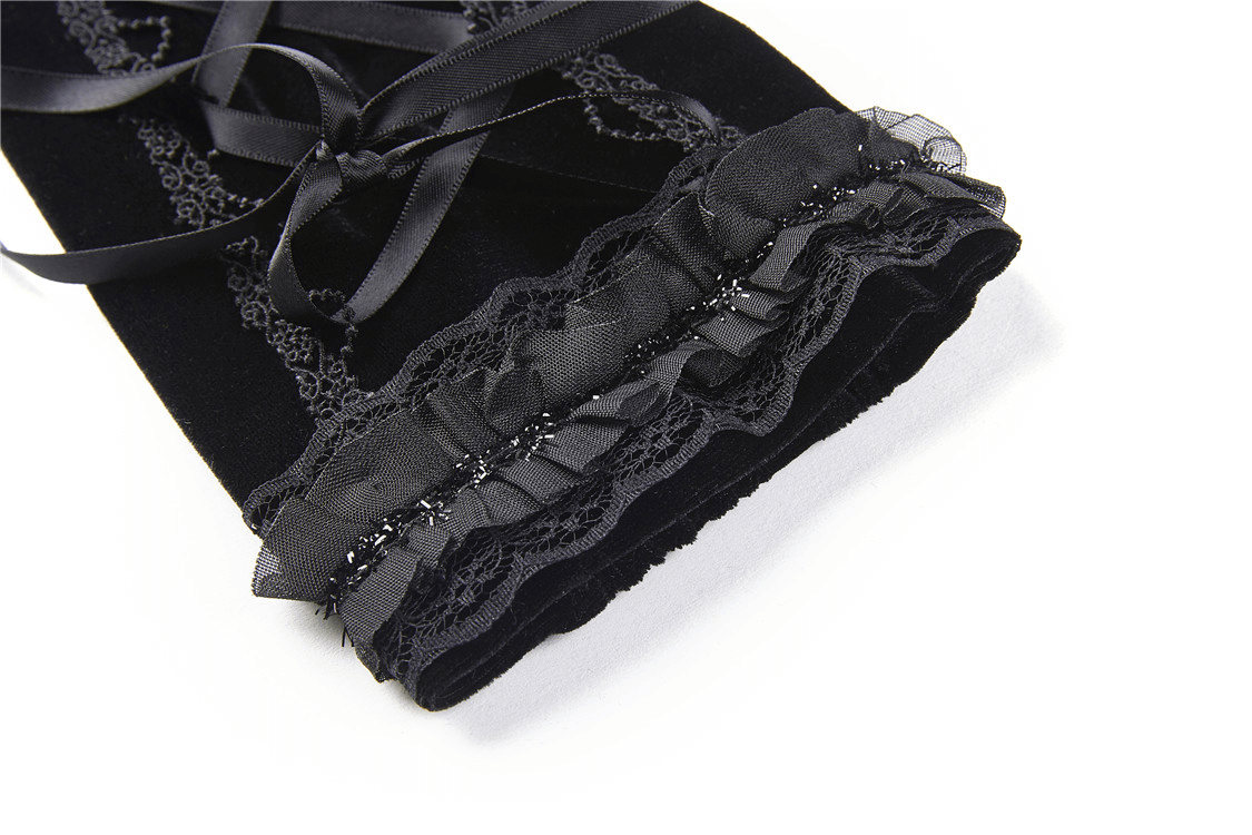 Close-up of black velvet fingerless gloves with lace detailing and ribbon ties, perfect for gothic fashion lovers.
