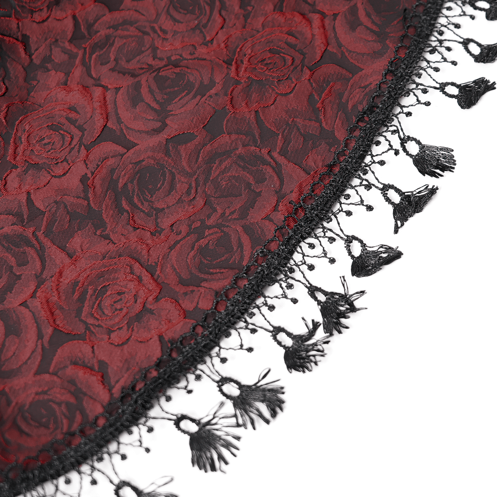 Close-up of red rose-patterned fabric with intricate black lace trim and tassel details, perfect for gothic fashion.