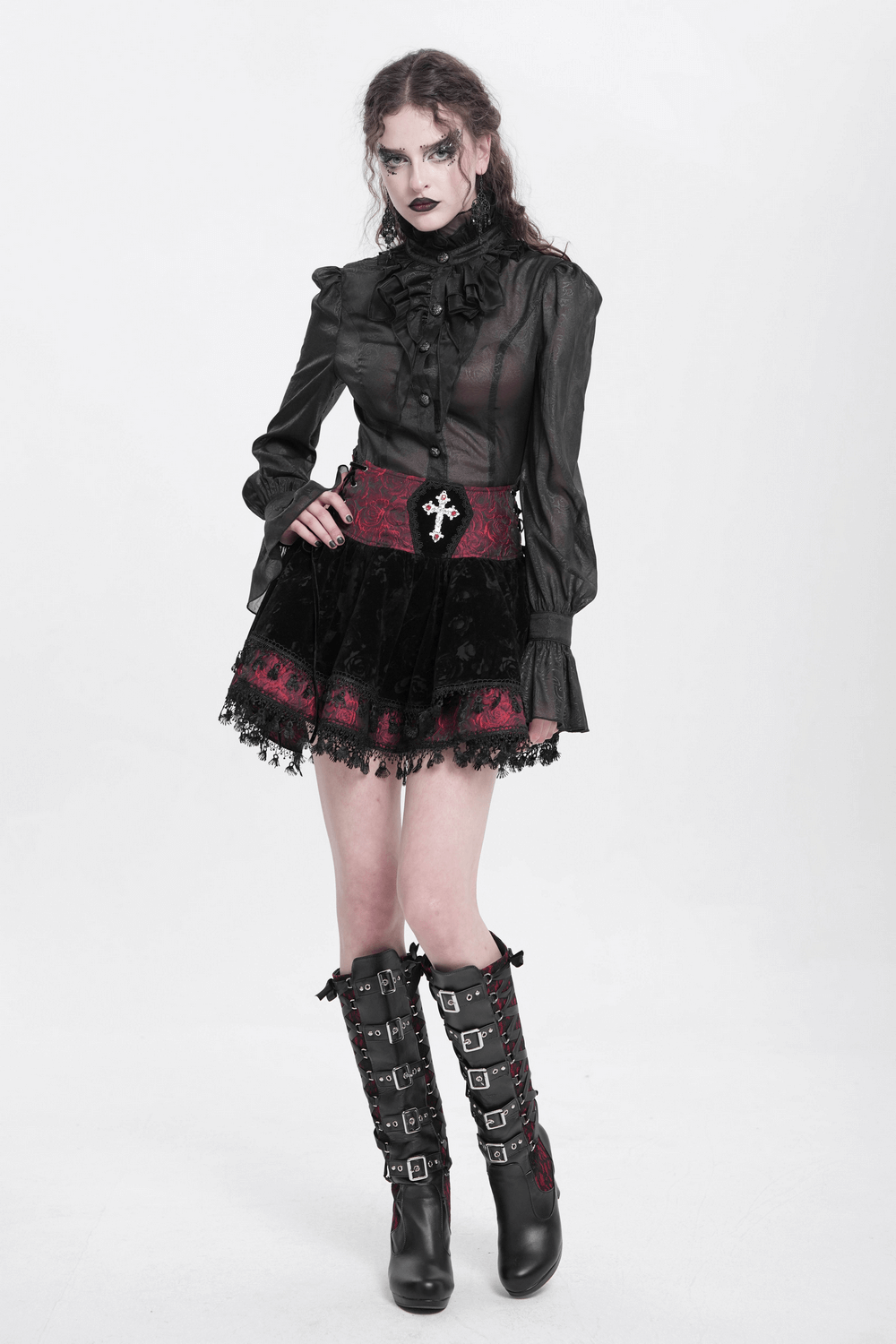 Gothic lace-up velvet skirt with embroidered cross, paired with a sheer blouse and stylish knee-high boots.