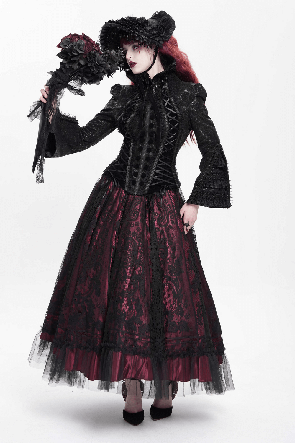 Gothic Lace-Up Victorian Jacket with Bell Sleeves and Cross worn by a model in a dramatic outfit holding a bouquet.