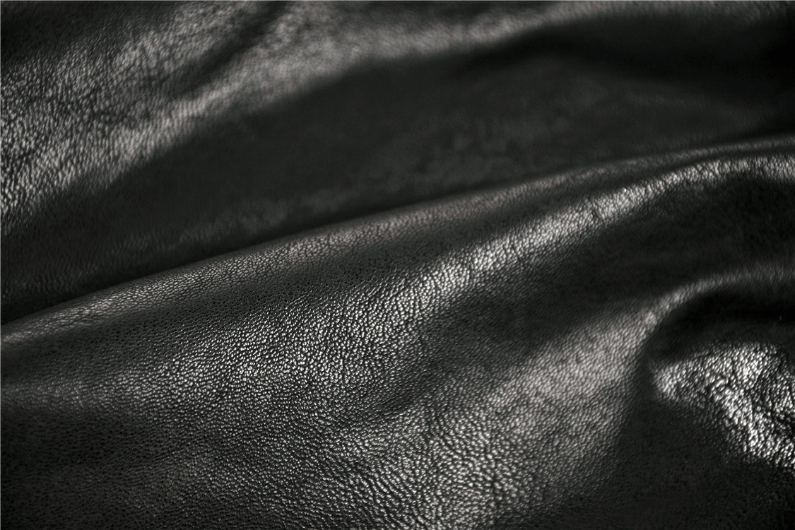 Close-up of luxurious black faux leather fabric, showcasing texture and sheen for gothic fashion garments.