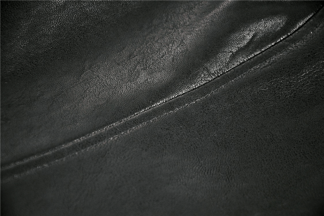 Close-up of sleek black leather texture featuring a subtle seam, perfect for gothic fashion inspiration.