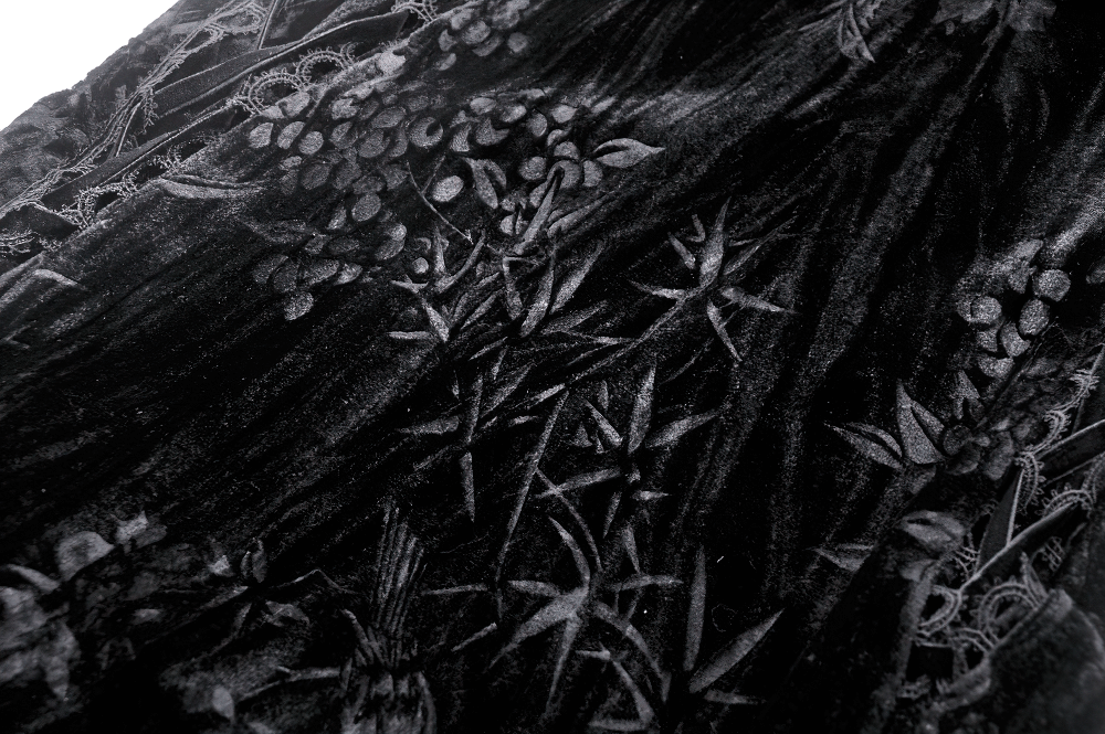 Close-up of intricate black velvet fabric with floral and lace patterns, perfect for gothic elegance.