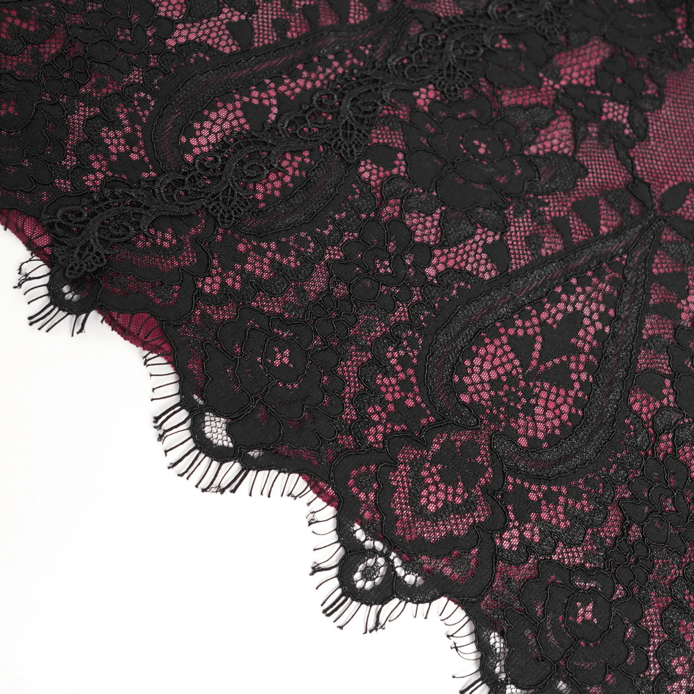 Close-up of gothic black lace over wine red fabric, showcasing intricate floral patterns and delicate fringed edges.