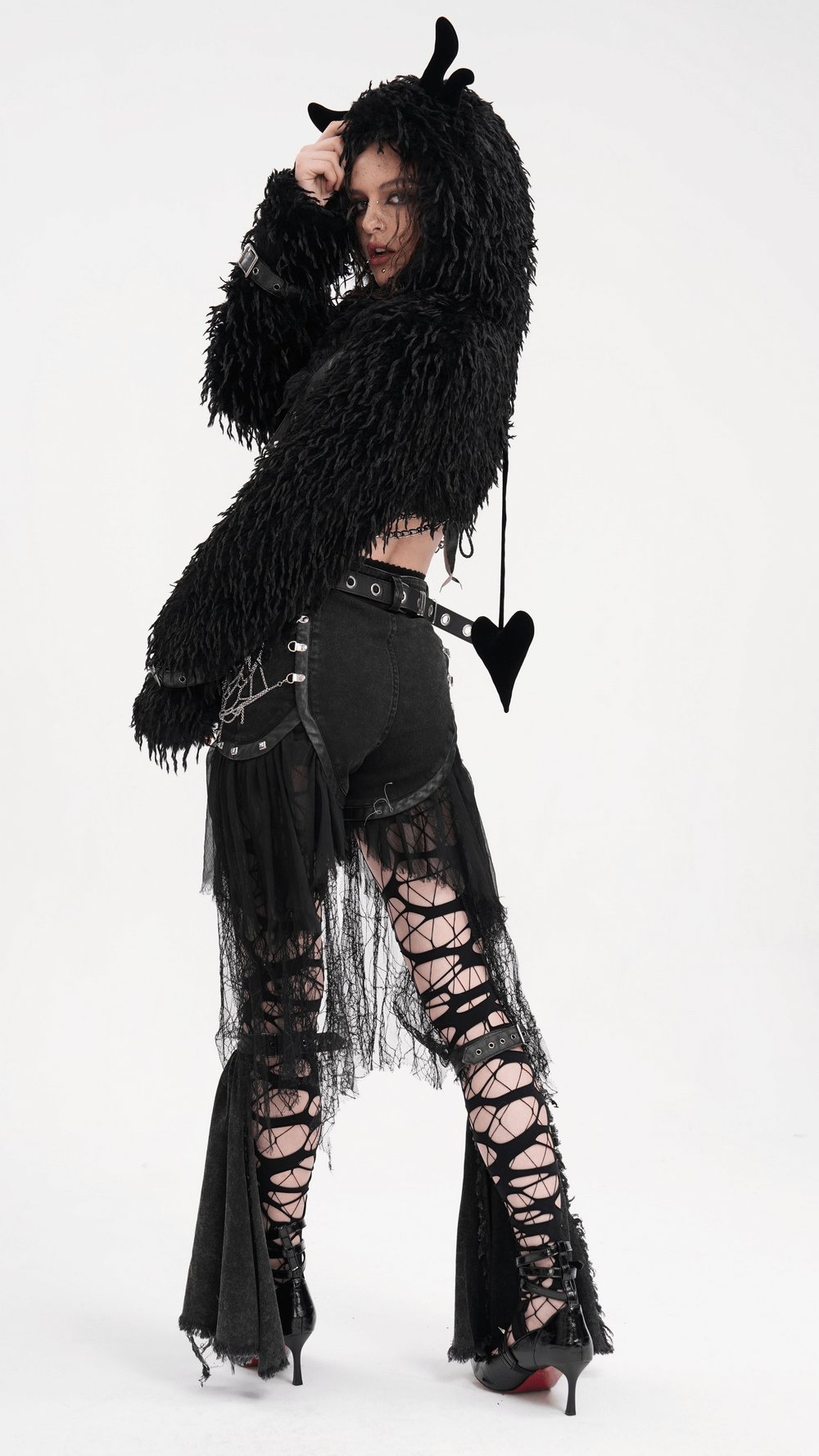 Edgy model in black gothic layered outfit with fringed jacket and tulle shorts, showcasing punk style and dramatic details.