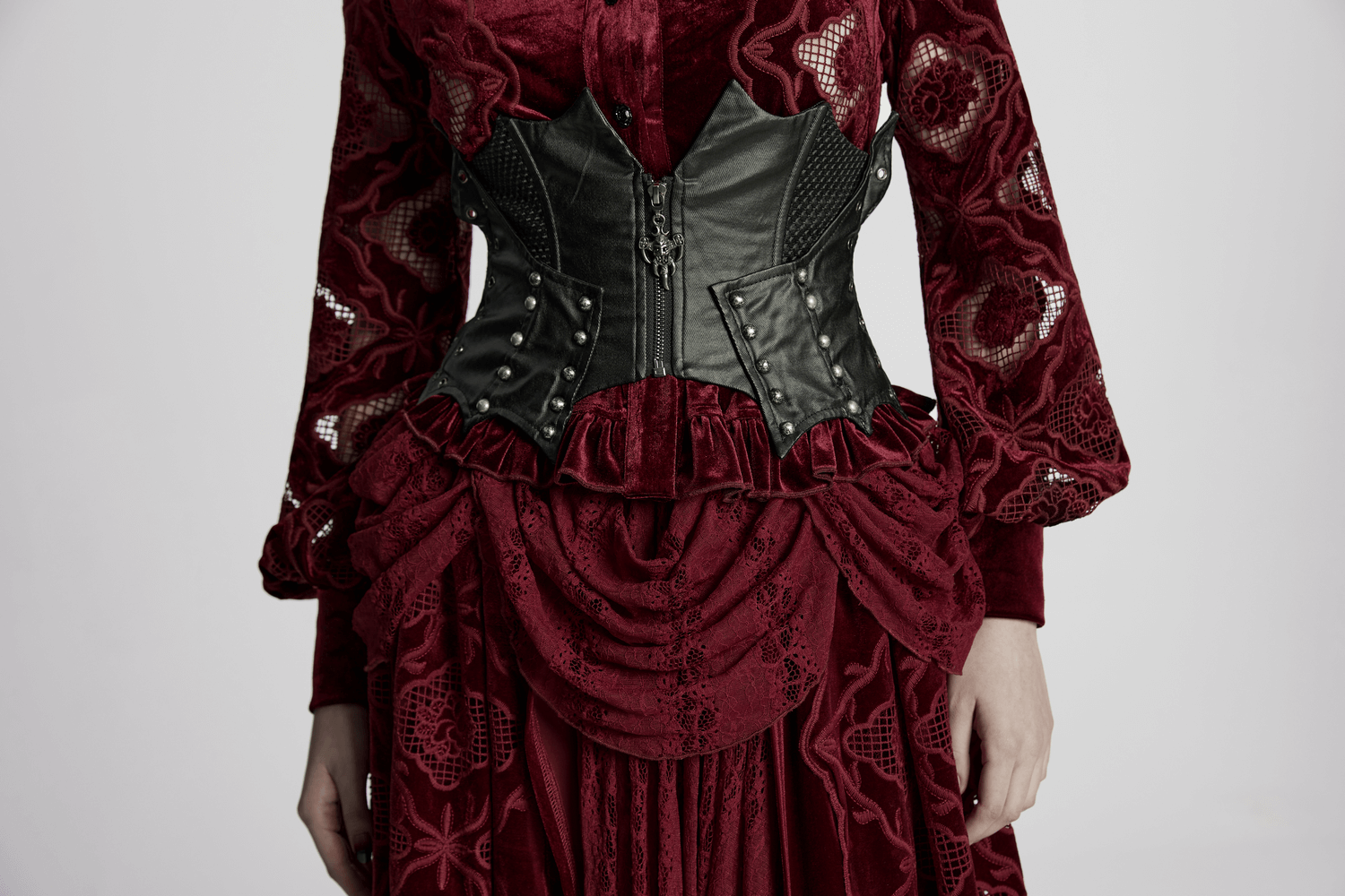 Gothic leather waist corset with studs and zipper, paired with a rich velvet dress, perfect for punk or Victorian styles.